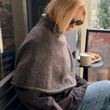 Frau trägt die Heia Tweedcape von Rauma, gestrickt aus Fivel 214 und Alpakka Lin Tweed 21798, mit breiten Rippenkanten