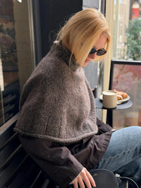 Frau trägt die Heia Tweedcape von Rauma, gestrickt aus Fivel 214 und Alpakka Lin Tweed 21798, mit breiten Rippenkanten