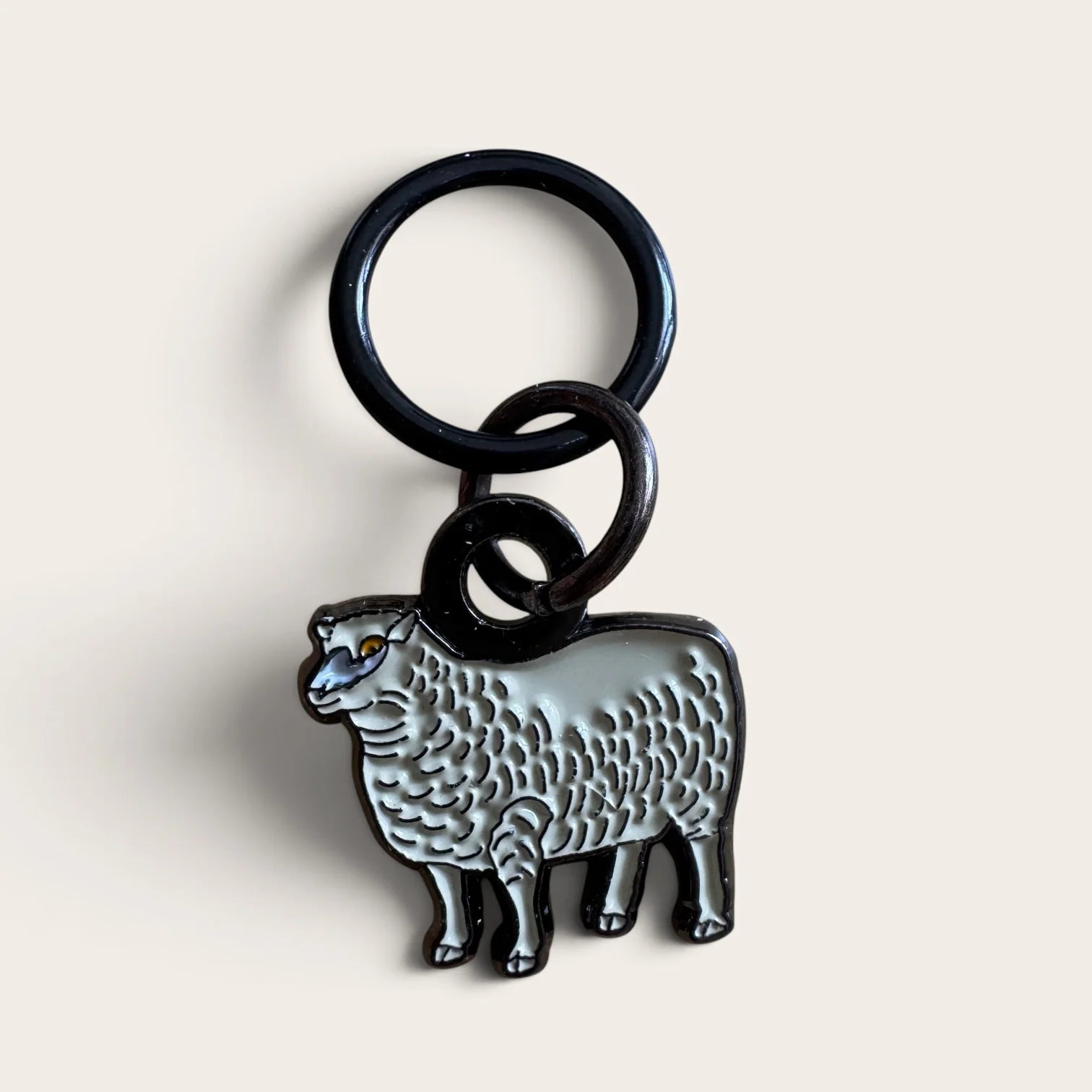 Firefly Notes Maschenmarkierer Meadow Sheep aus Metall und Emaille, cremeweißes Schaf mit schwarzem Ring, Nahaufnahme auf hellem Hintergrund