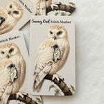 Firefly Notes Maschenmarkierer Snowy Owl aus Metall und Emaille, cremeweiße Schneeeule mit schwarzem Ring auf heller Karte mit Vintage-Illustration einer Schneeeule auf einem Ast