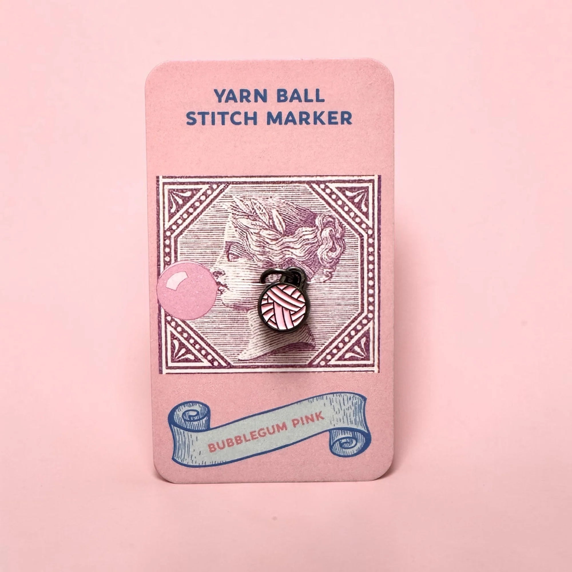 Firefly Notes Maschenmarkierer Yarn Ball in Bubblegum Pink aus Metall und Emaille, rosa Wollknäuel mit schwarzem Ring auf rosa Karte mit Vintage-Briefmarke und Frauenprofil mit Kaugummiblase