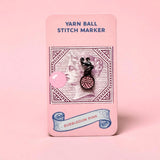 Firefly Notes Maschenmarkierer Yarn Ball in Bubblegum Pink aus Metall und Emaille, rosa Wollknäuel mit schwarzem Hakenverschluss auf rosa Karte mit Vintage-Briefmarkenmotiv