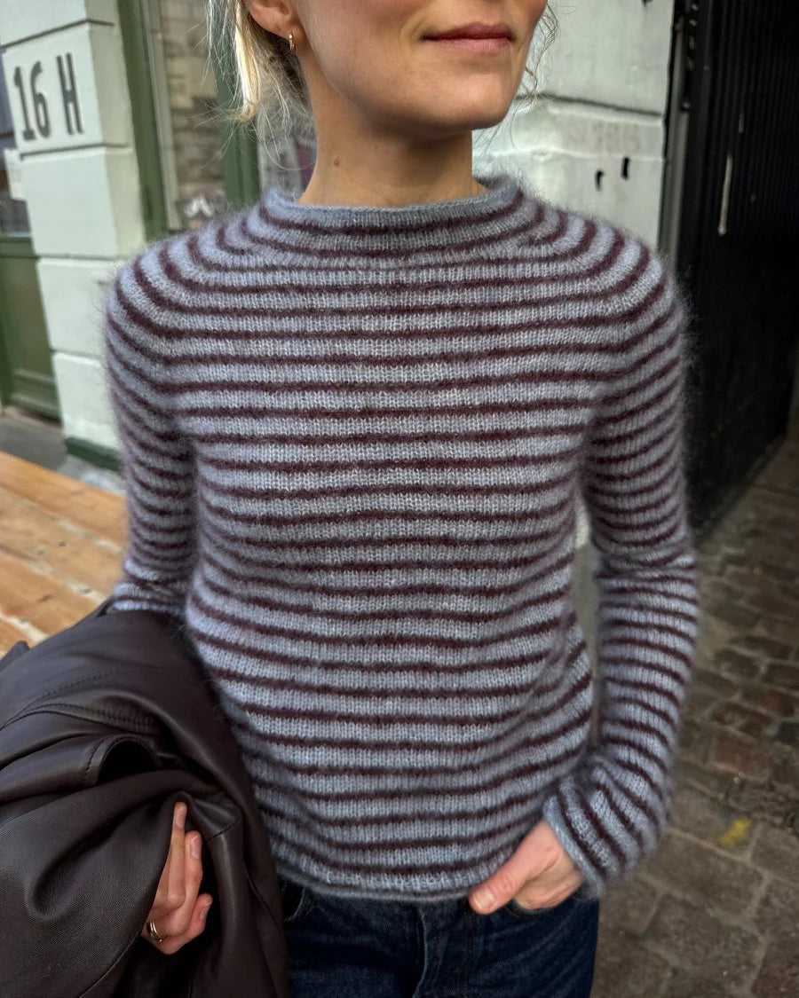 Frau trägt die Frankie Blouse von PetiteKnit in Blau mit schmalen bordeauxfarbenen Streifen – Strickset mit Isager Silk Mohair