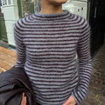 Frau trägt die Frankie Blouse von PetiteKnit in Blau mit schmalen bordeauxfarbenen Streifen – Strickset mit Isager Silk Mohair