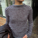 Frau trägt die Frankie Blouse von PetiteKnit in Blau mit schmalen bordeauxfarbenen Streifen – Strickset mit Isager Silk Mohair